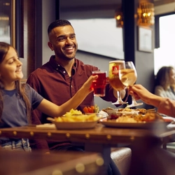 Friends raising their drinks over a meal together at the pub