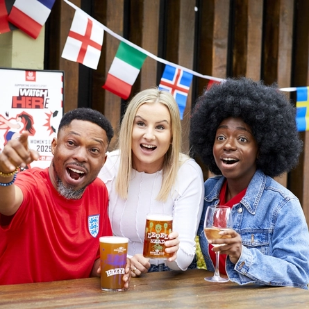 A mixed group of people, sitting at an outdoor table, reacting to a sport event.