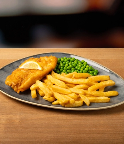 A plate of fish and chips on a wooden table.