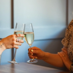 Two women sat at an indoor table, enjoying a glass of sparkling wine.