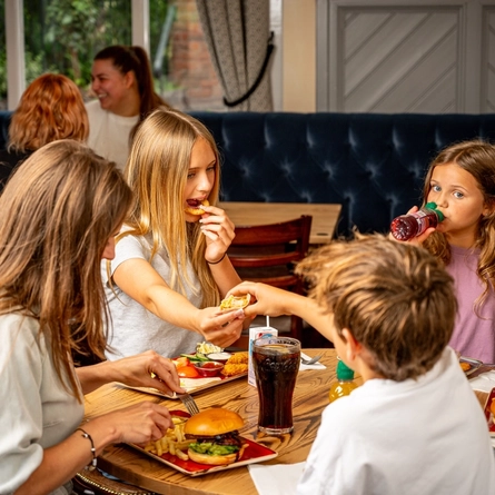A family sat at an indoor table enjoying a meal and drinks at a Hungry Horse venue.