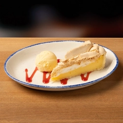A plated Lemon Meringue and ice cream on a wooden table.