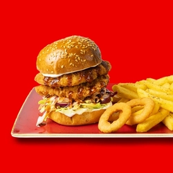 The Hungry Horse Korean BBQ Chicken Burger served on a red plate with fries and onion rings; on a bright red background.